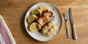 Slices of traditional Czech bramborové knedlíky served with roast pork
