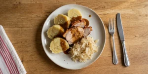 Slices of traditional Czech bramborové knedlíky served with roast pork