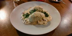 A steaming plate of authentic Lithuanian cepelinai, large oval potato dumplings topped with a rich sauce.