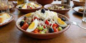 Bulgarian Ovcharska Salata decorated with hard-boiled eggs, olives, and grated cheese