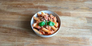 Pasta alla Norma served in a bowl with fresh basil leaves and tomato sauce