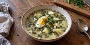 A bowl of hot Lithuanian green sorrel soup served with a hard-boiled egg