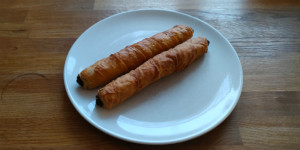 A platter of golden-fried Turkish sigara böreği garnished with fresh parsley and lemon wedges